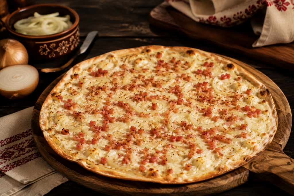 Tarte flambée végétarienne aux bords croustillants garnie d'oignons et de lardons végétaux, servie sur une planche en bois dans une ambiance chaleureuse.