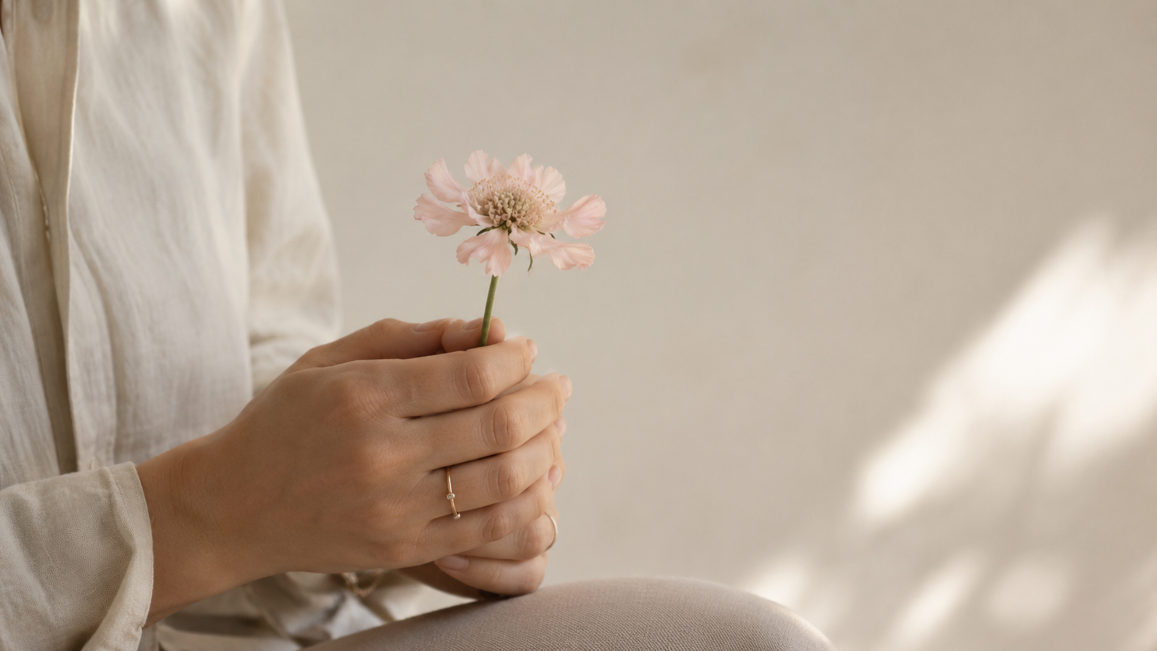Mains d'une femme tenant une fleur délicate, symbole de douceur et de soutien après une fausse couche.
